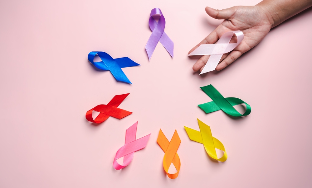 Hand Holding Pink Ribbon Which Is Among Colorful Ribbons