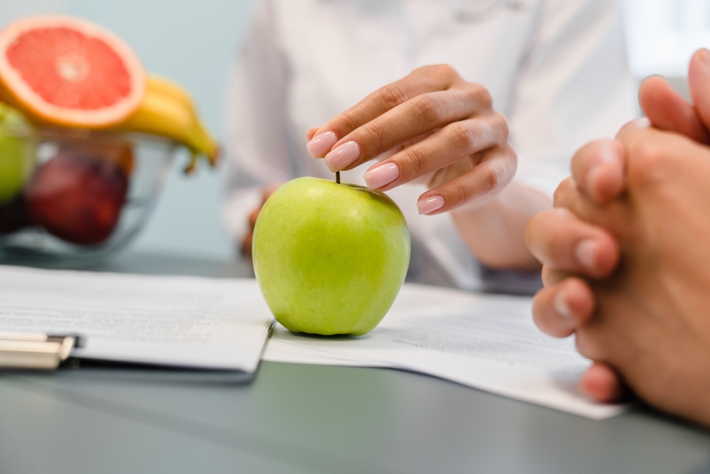 Cropped Close Up Shot Of Green Apple On Dietitian Desk