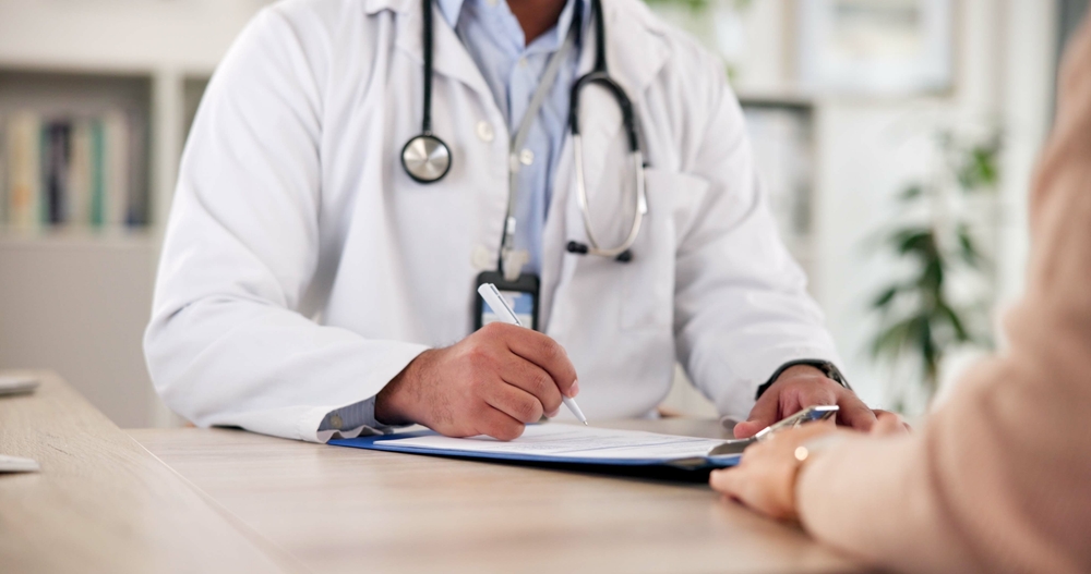 HandsPersonAndDoctorWithClipboardInOfficeForAssessment Hands Person And Doctor With Clipboard In Office For Assessment