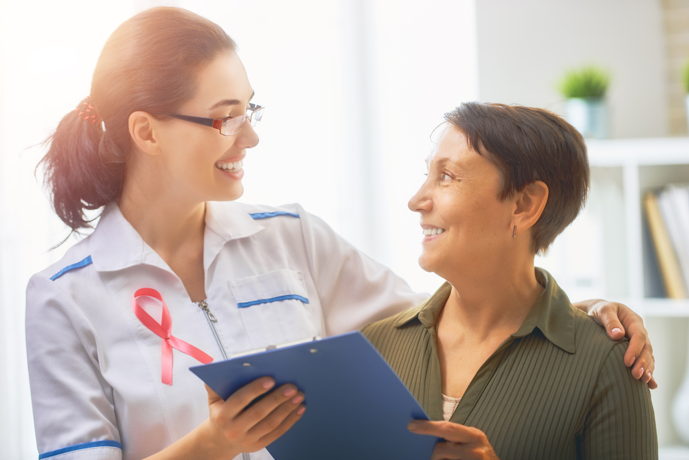 PinkRibbonForBreastCancerAwarenessFemalePatientListeningTo Pink Ribbon For Breast Cancer Awareness Female Patient Listening To