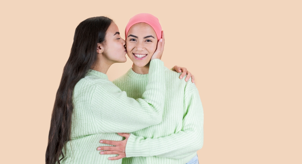Two Women Twin Sisters Fighting Cancer Kiss The Face.