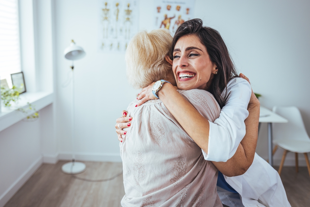 Senior Woman Hug Or Medical Caregiver In House Living Room