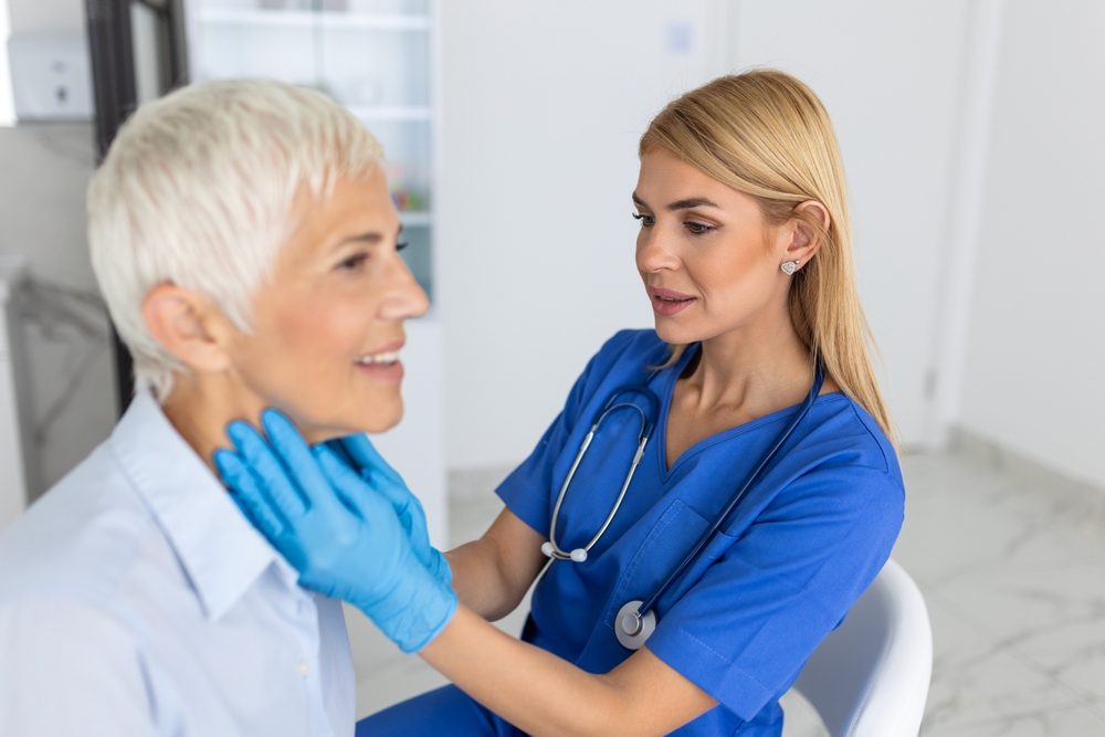 Friendly Woman Doctor Wearing Gloves Checking Sore Throat Or Thyroid