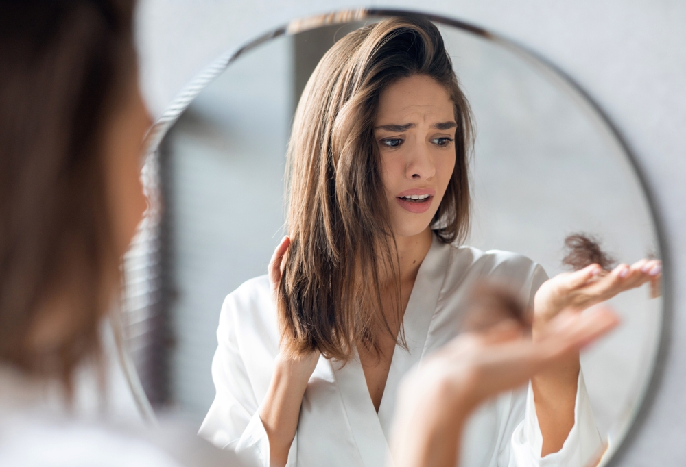 Hairloss Concept. Worried Young Woman Holding Bunch Of Fallen Hair
