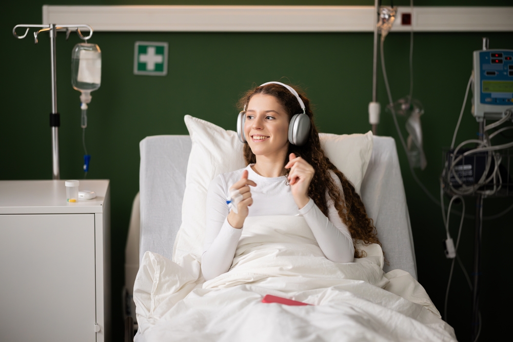 Young Woman Lies In A Hospital Room Enjoying Music Through