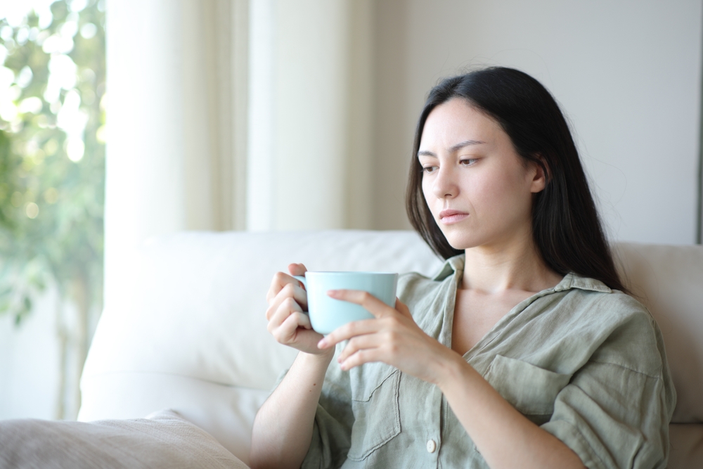 Apathetic Asian Woman Drinking And Complaining Sitting A Sofa