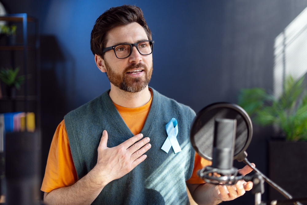 Radio Host Wearing Light Blue Ribbon Talking About Prostate Cancer