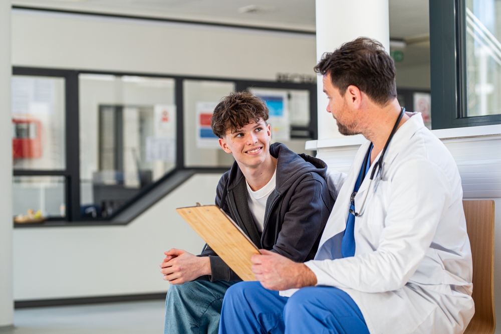 Teenage Boy Smiling Talking With Doctor Receiving Positive Health News.