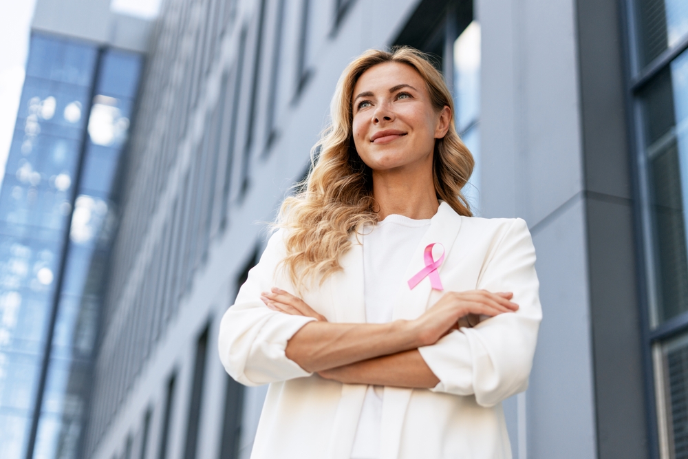 Businesswoman Wearing Pink Ribbon Is Crossing Arms And Looking Up