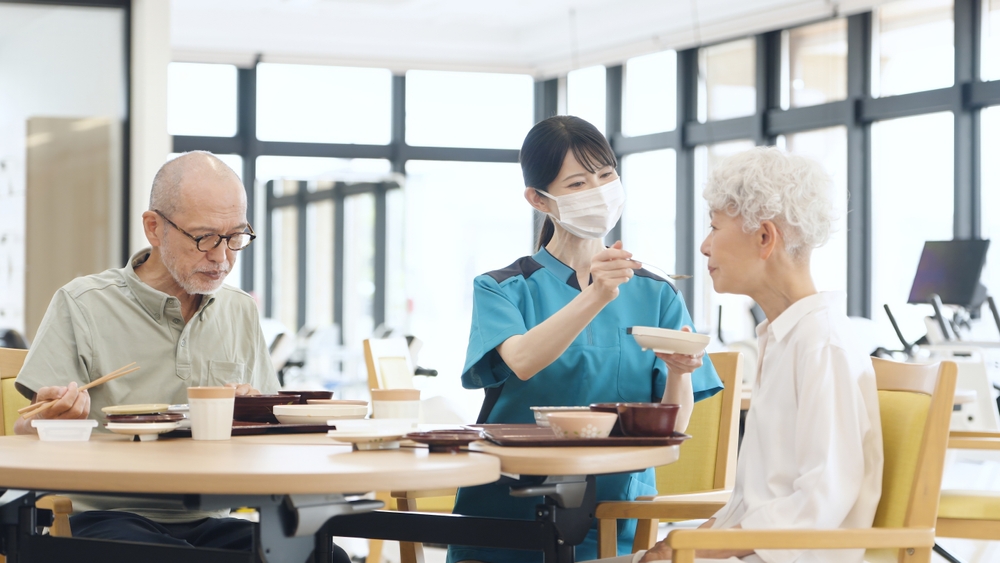 Asian Caregiver Assisting With Meals