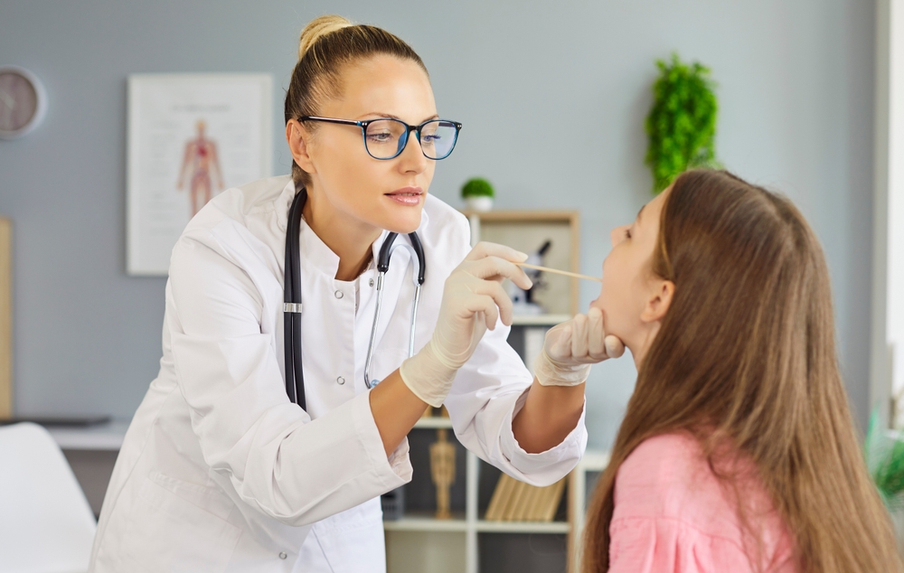 Pediatrician Swabs Child Patient Throat For Test. The Doctor At