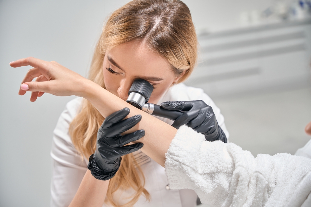 Female Cosmetologist Examining Hand Skin With Dermatoscope Of Cropped Woman