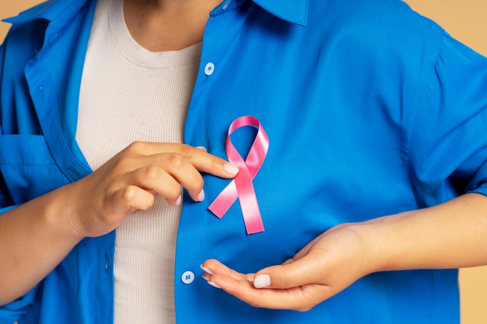 Woman Wearing Blue Is Attaching A Pink Ribbon To Her